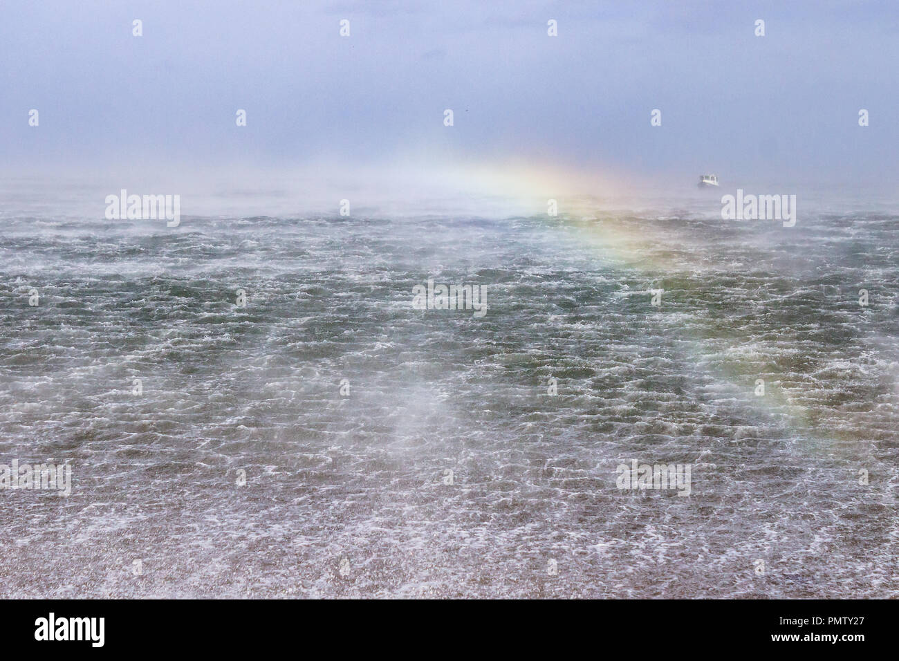 Effet arc-en-ciel sur la mer comme des vagues et spray attisé par de forts vents de tempête au cours de la capture du soleil. Ali Newton faible par la mer, Northumberland, Angleterre. 19 septembre 2018. Banque D'Images