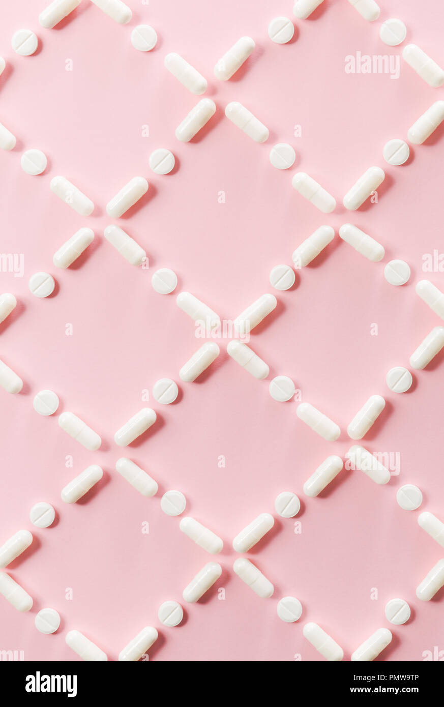 Modèle de pilules et de comprimés blancs sur fond rose. Banque D'Images