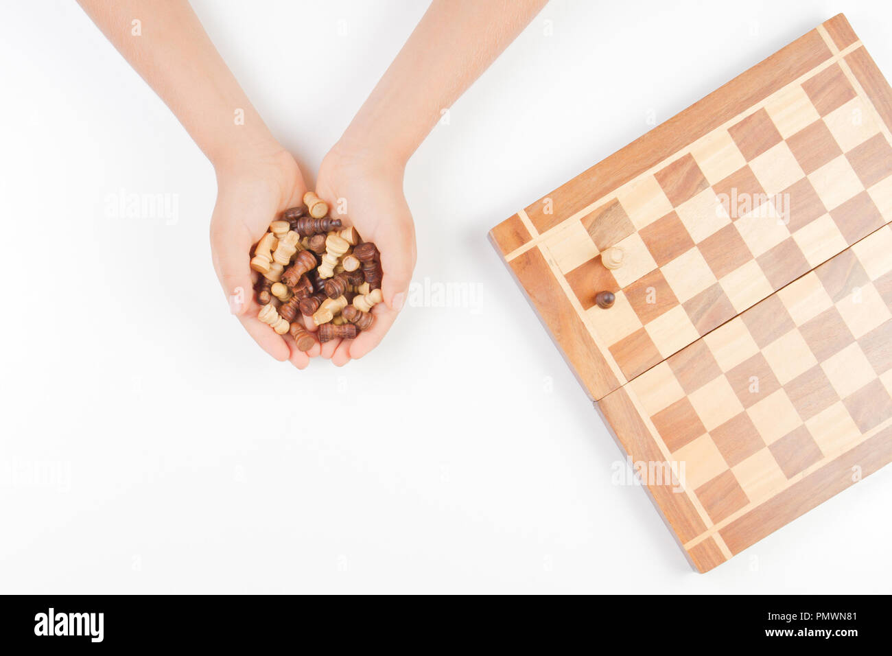 Vue du dessus de l'enfant les mains avec pièces d'échecs et d'échecs sur fond blanc Banque D'Images