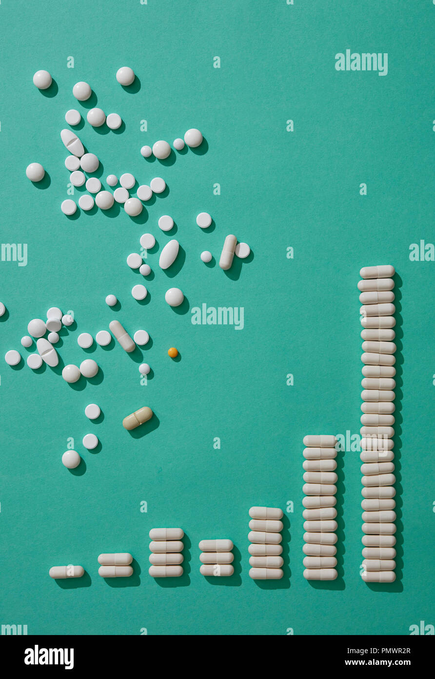 Comprimés capsules ci-dessus dispersés formant bande lumineuse croissante sur fond vert Banque D'Images