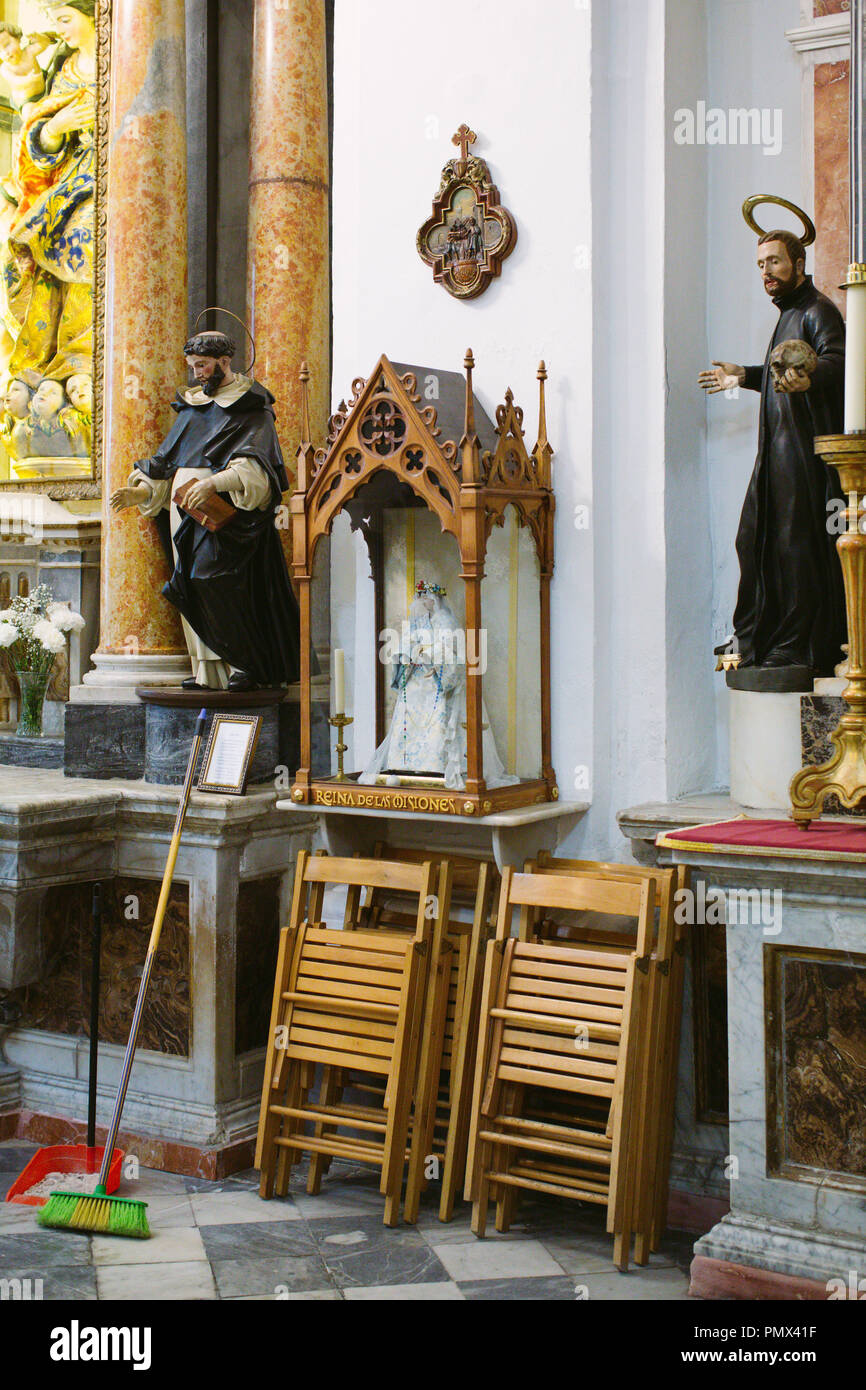 Scène candide de nettoyage (Pelle et brosse) et chaises repliées appuyé contre un saint et icônes religieuses dans une église Banque D'Images