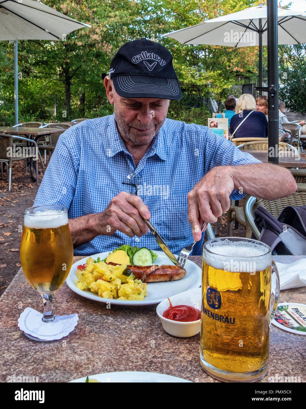 Berlin, Neukölln, Britzer Jardin. Hauts homme jouit le déjeuner de saucisses, salade de pomme de terre et la moutarde à la bière avec repas table d'extérieur de snack-bar offrant te Banque D'Images