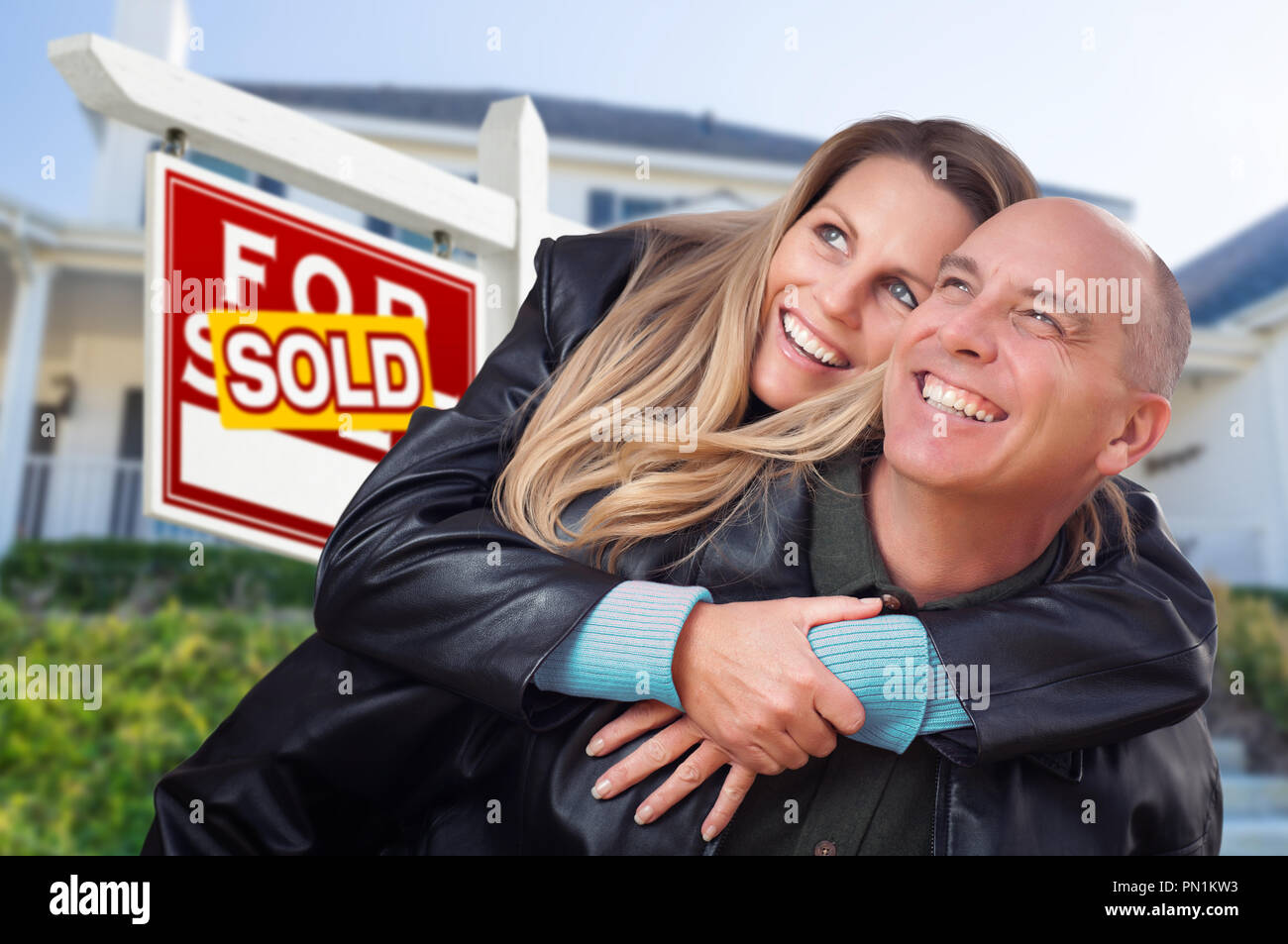 Heureux Couple Hugging in front of vendu enseigne immobilière et de la Chambre. Banque D'Images