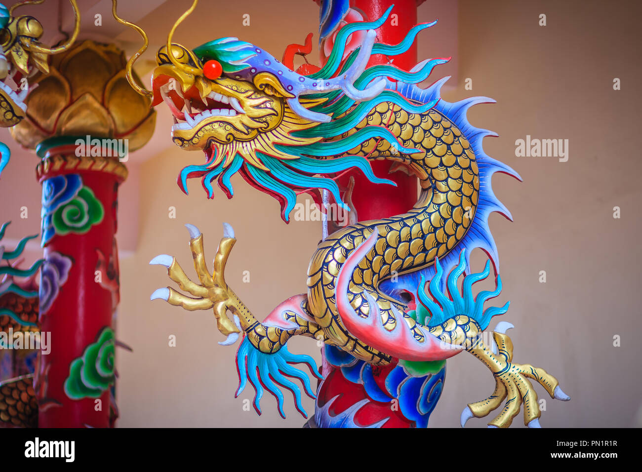 Statue de dragon chinois coloré enroulé autour du pilier rouge. Belle statue de dragon sculptée autour de temple en pôle public chinois temple. Banque D'Images