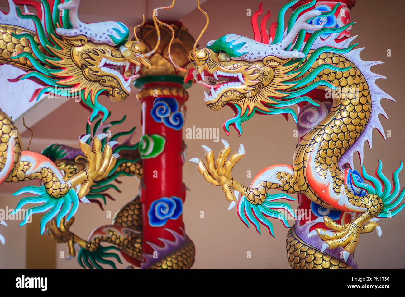 Statue de dragon chinois coloré enroulé autour du pilier rouge. Belle statue de dragon sculptée autour de temple en pôle public chinois temple. Banque D'Images