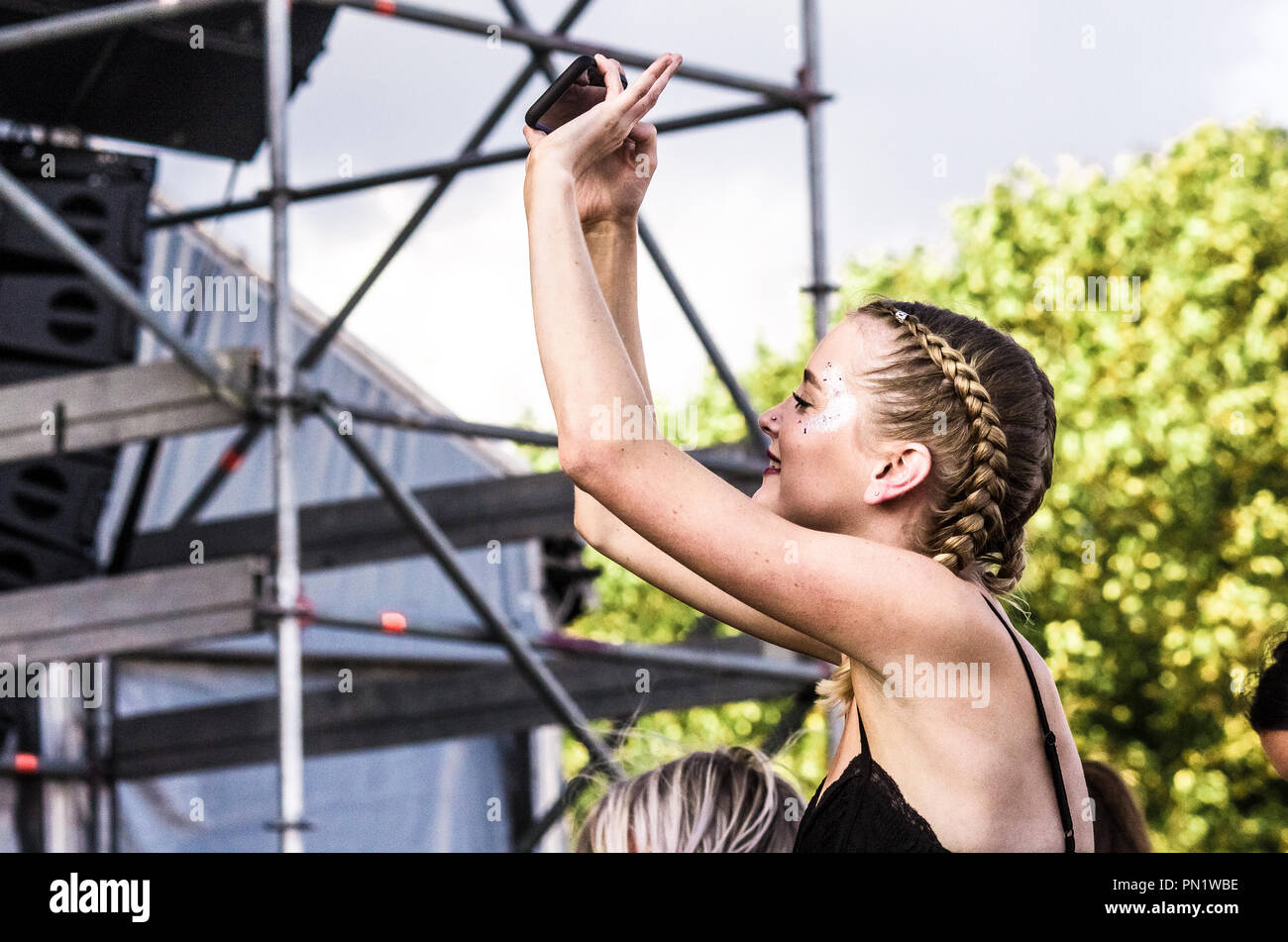 Fille/Femme prenant une bande selfies en regardant un alors que sur les épaules de quelqu'un à un festival de musique, au Royaume-Uni. Banque D'Images