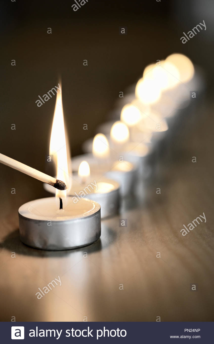 Une rangée de bougies à réchaud étant allumé avec une allumette Banque D'Images