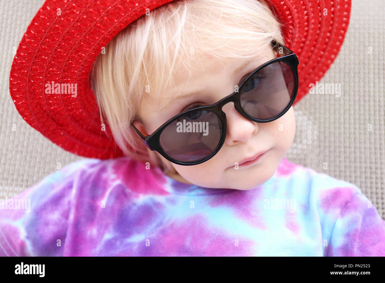 Un Mignon Petit Bebe Fille De 2 Ans Est A L Exterieur De Soleil Portant Un Chapeau Et Des Lunettes De L Ete Comme Elle L Appareil Photo A Loos De Serieux Photo Stock