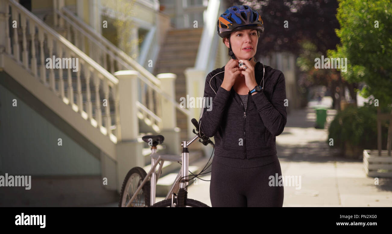 Caucasian woman in athletic wear debout avec vélo dans le centre-ville de quartier Banque D'Images