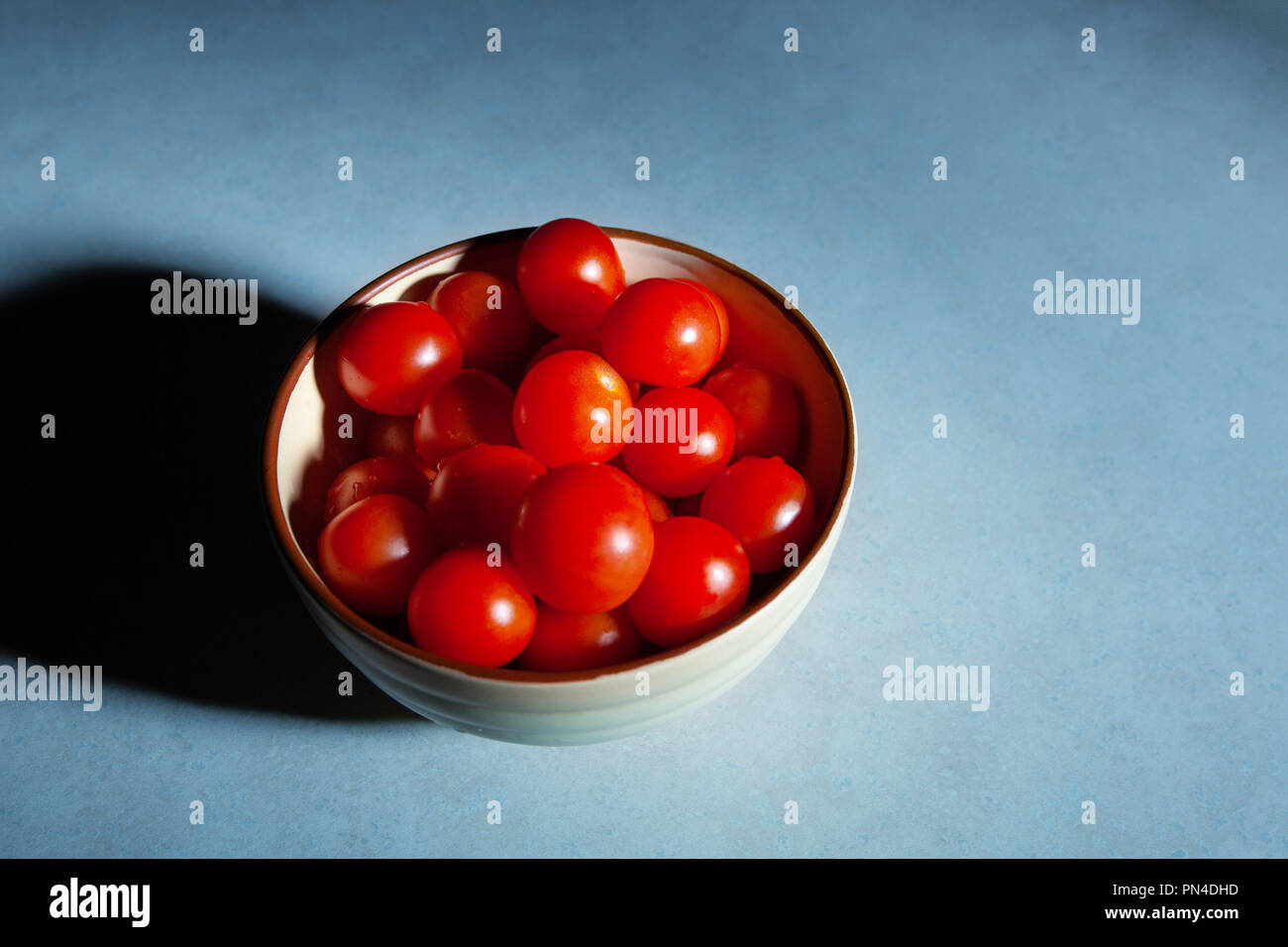 Les tomates cerise dans le bol sur la table avec des grungy light top view with copy space Banque D'Images