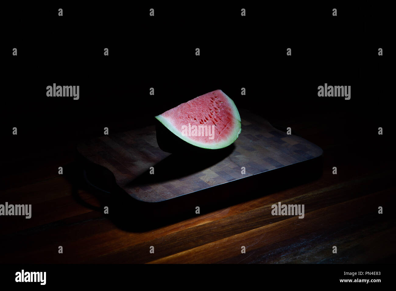 Watermelon slice on chopping board sur fond noir avec lumière Banque D'Images