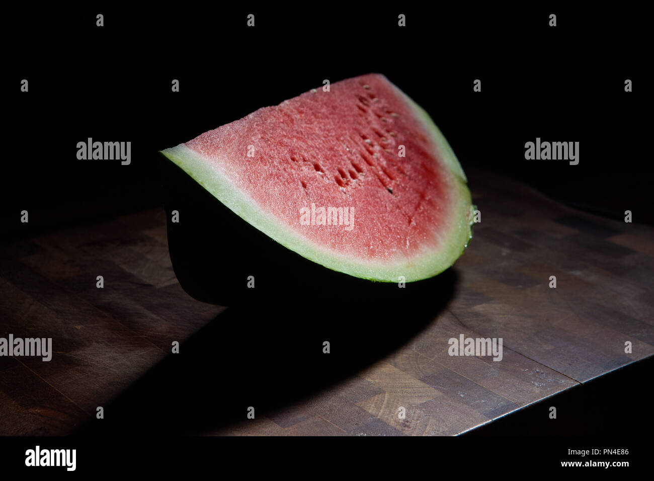 Watermelon slice on chopping board extreme gros plan sur fond noir avec lumière Banque D'Images