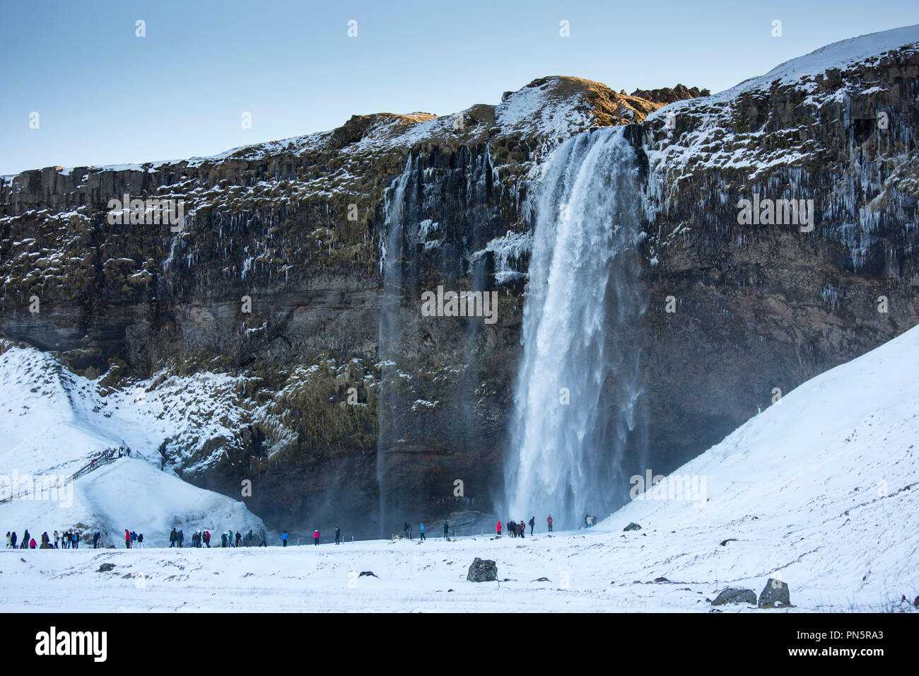 Les touristes à la spectaculaire cascade de Seljalandsfoss dans le sud de l'Islande avec les eaux de la fonte des inlandsis Eyjafjahajokul Banque D'Images