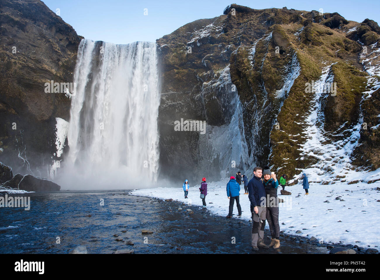 Les touristes à Skogar spectaculaire waterfall - Skogar - dans le sud de l'Islande avec les eaux de fusion glaciaire jaillissant Banque D'Images