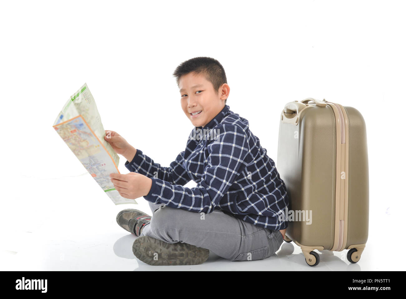 Asian boy holding map et assis avec assurance, isolé sur blanc. Banque D'Images