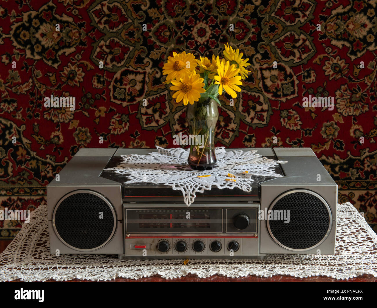 Vieille radio sur la table avec une horloge et un vase de fleurs Banque D'Images