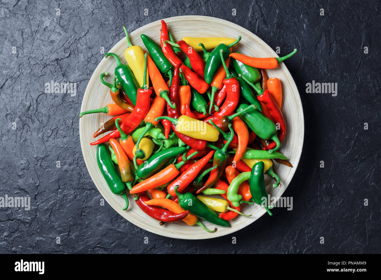 Différentes couleurs hot peppers en plaque de bois Banque D'Images