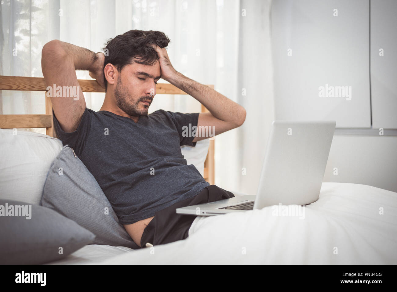 L'homme stressé de travailler avec un ordinateur portable dans la chambre. La technologie et le style de concept. Les questions sociales et de problème. Les soins de santé et le syndrome de bureau. Econom Banque D'Images