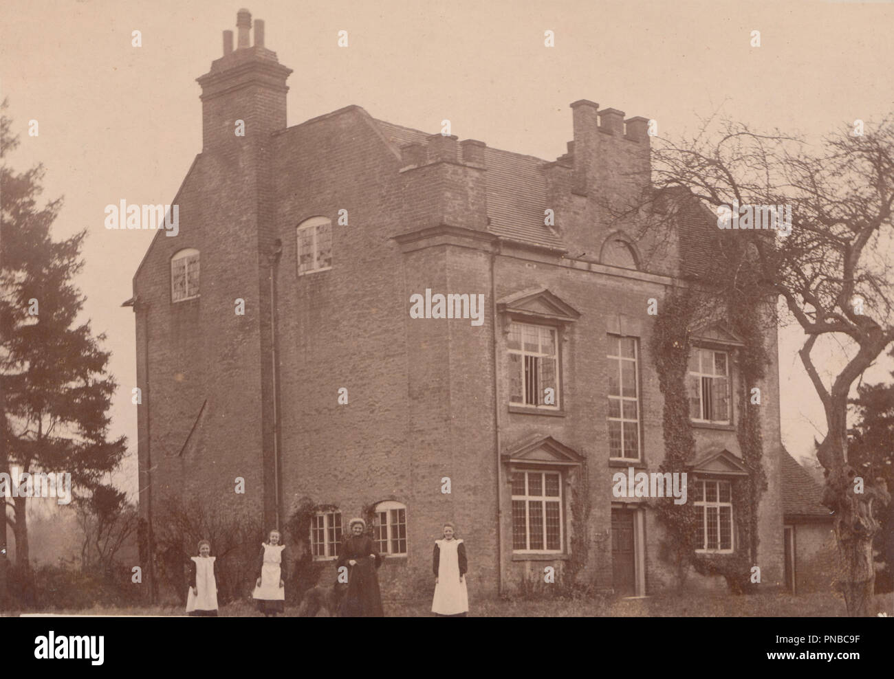 * Vintage Photo d'une grande Maison Individuelle Maison britannique. Dame et trois jeunes filles posant dans le jardin de devant Banque D'Images