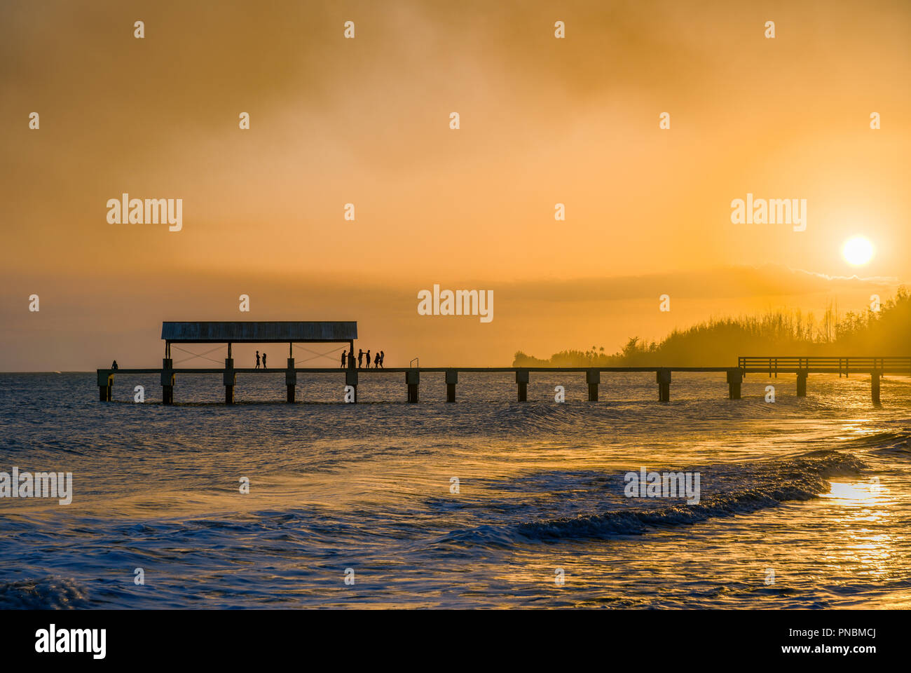 Coucher du soleil à l'Embarcadère de Waimea à proximité comme une traînée de fumée remplit le ciel Banque D'Images