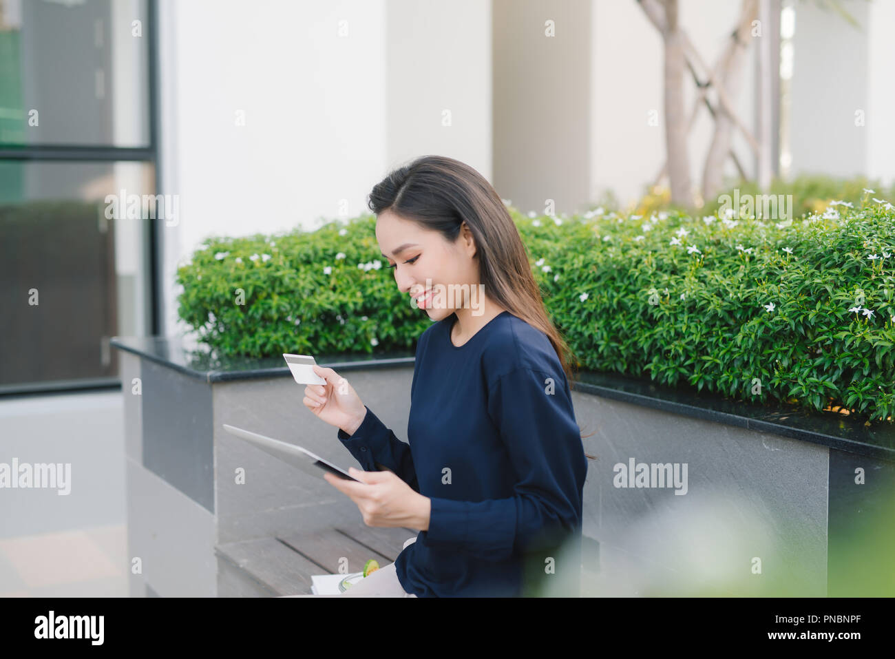 Une jolie jeune femme d'affaires asiatique sur un banc à l'extérieur de bâtiment de bureaux Banque D'Images