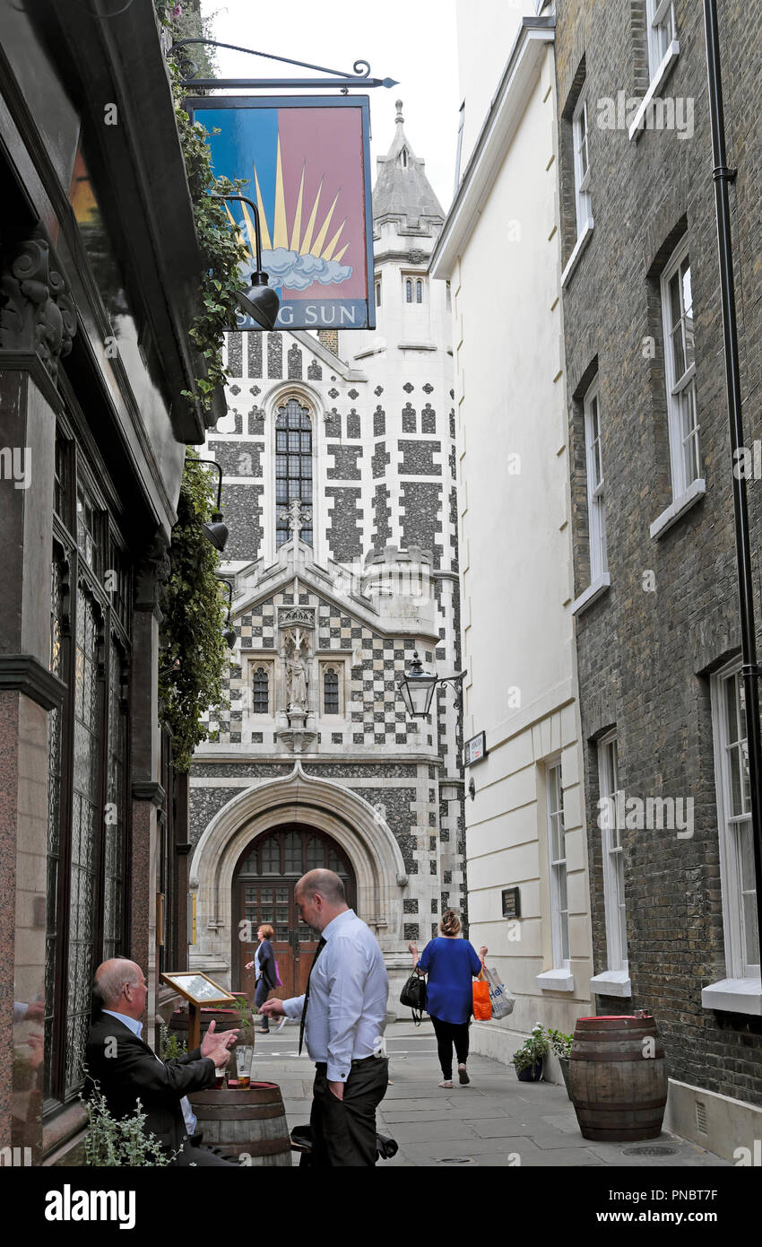 Les hommes de boire une bière à l'extérieur du Soleil Levant pub avec une vue de la grande église St Barthélemy à Smithfield London EC2 England UK KATHY DEWITT Banque D'Images
