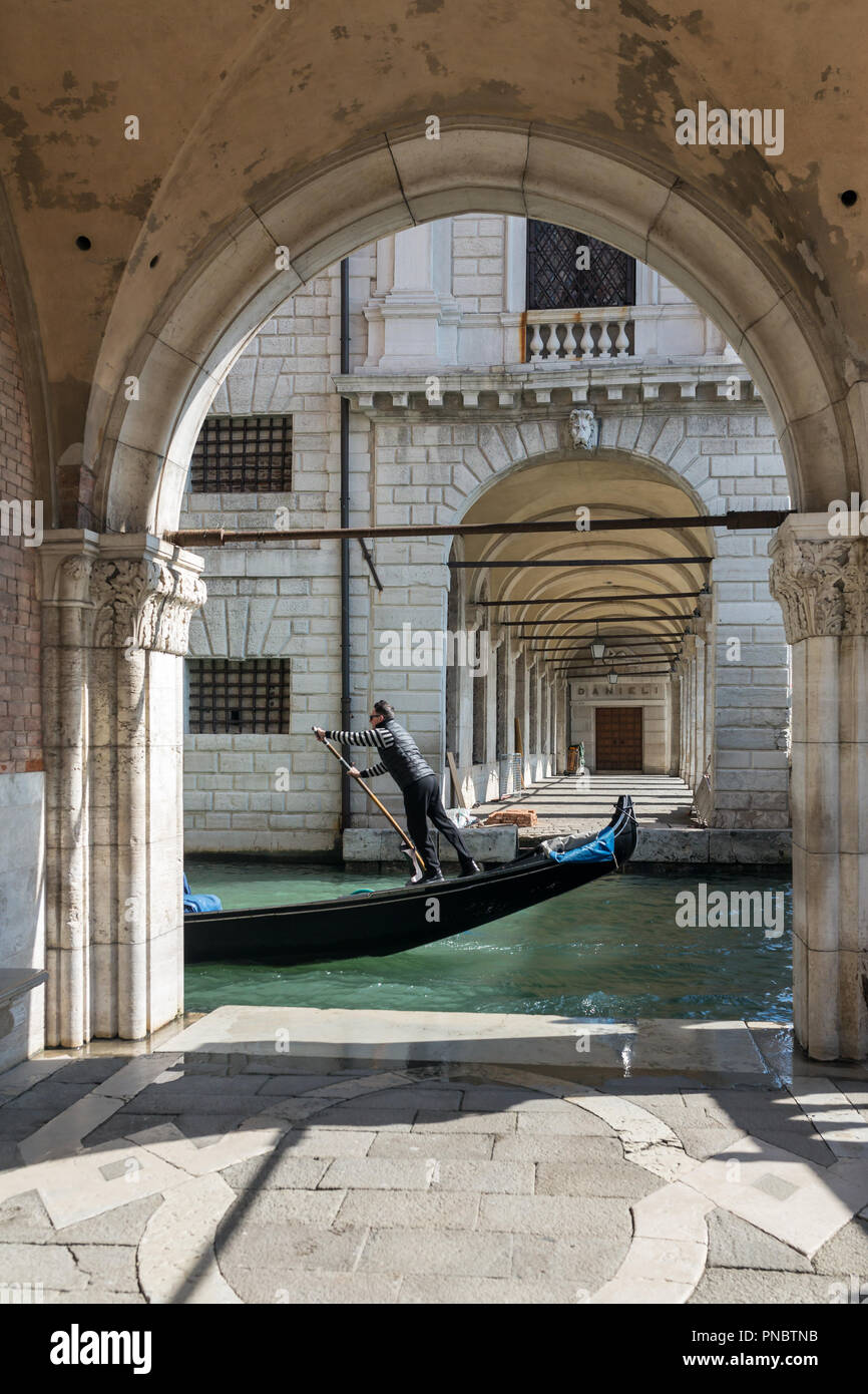 Venise, Italie - 21 mars 2018 : Venetian gondola gondolier équitation à travers le côté étroit canal à Venise. Banque D'Images