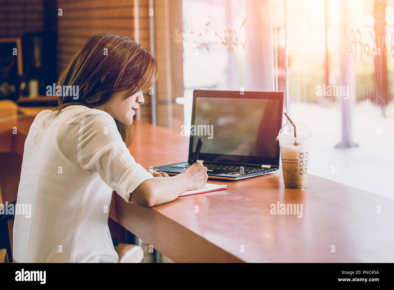Les femmes asiatiques woking au café avec un ordinateur portable et l'écriture note. penser projet d'entreprise à l'action. Banque D'Images