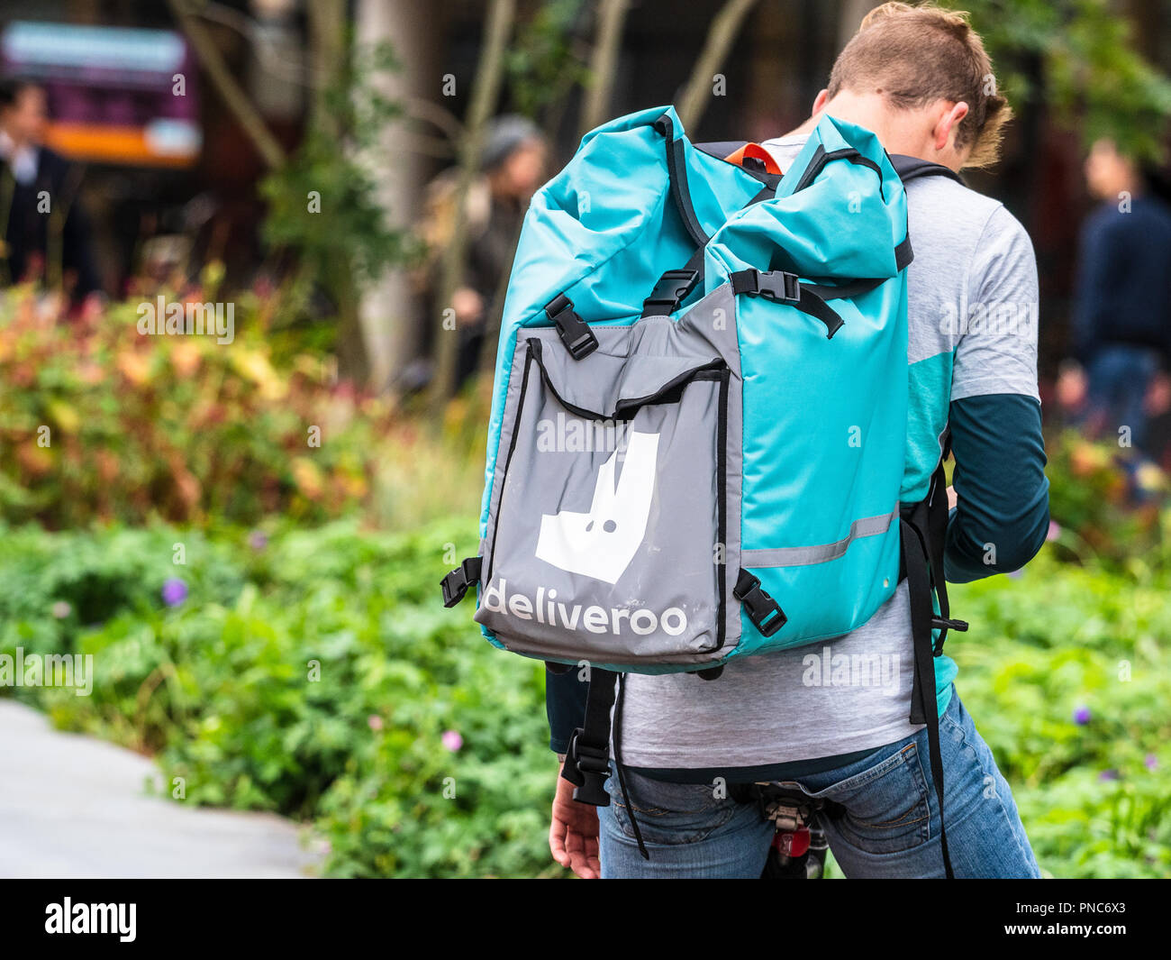 Deliveroo Courier Livraison de nourriture - un Deliveroo rider attend que le prochain travail de livraison de nourriture Banque D'Images