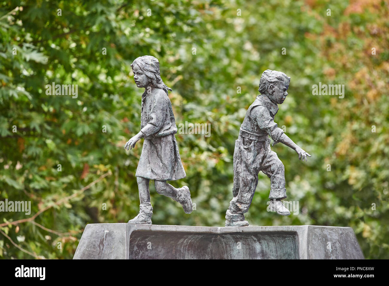 Statuettes Métal, d'un garçon et une fille courir dans une direction opposée, dans le centre commercial de Northampton, en Angleterre. Banque D'Images