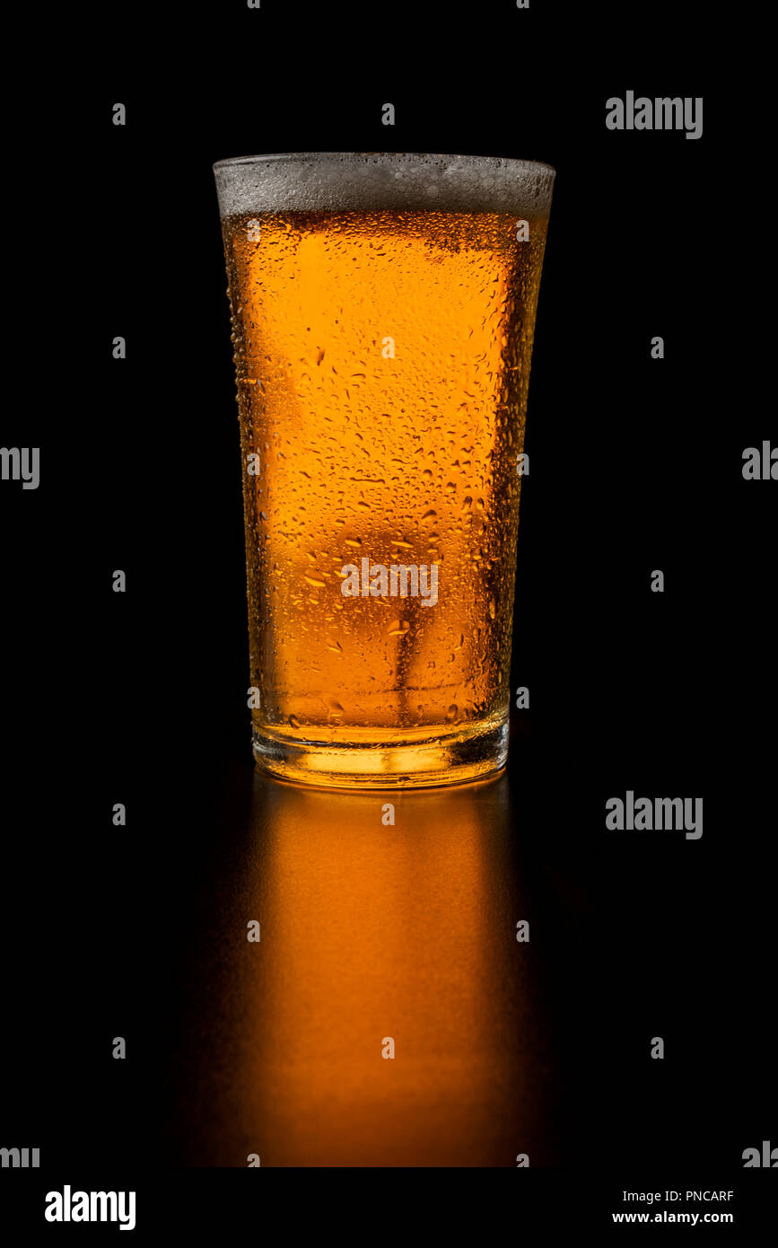 Verre de bière blonde sur fond noir Banque D'Images
