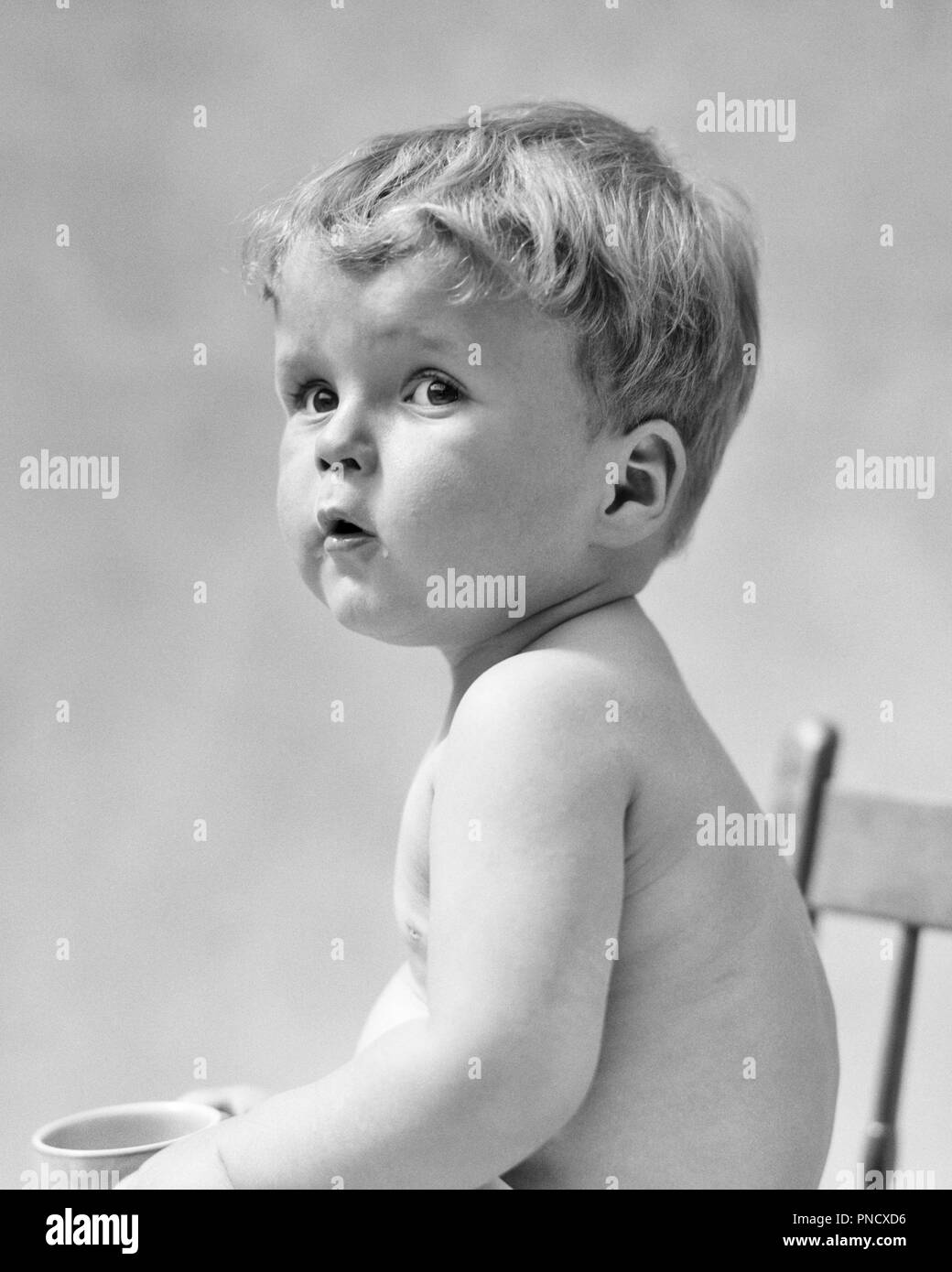 Années 1930 un BABY BOY SITTING IN CHAIR regardant par-dessus son épaule - b10400 HAR001 HARS incertain à l'ANCIENNE Banque D'Images