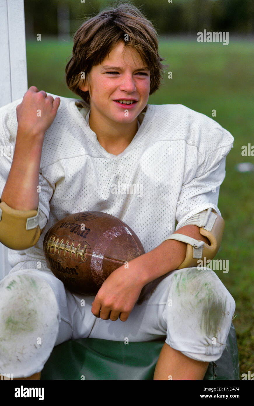 1980 SMILING BOY WEARING PRATIQUE UNIFORME DE FOOTBALL ASSIS SUR TERRAIN HOLDING FOOTBALL - kj9014 PHT001 HARS 1 OLD FASHION STYLE REMISE EN FORME DU VISAGE JUVÉNILE DE LA SÉCURITÉ DE L'ATHLÈTE DE LA CONCURRENCE SAINE HEUREUSE JOIE DE VIE SANTÉ RURALE mi-longueur ATHLÉTISME REMISE EN FORME PHYSIQUE PRATIQUE PERSONNES MÂLES ADOLESCENT RISQUE D'ACTIVITÉ PHYSIQUE LE BONHEUR DES EXPRESSIONS SPORTIVES FORCE JOYEUSE VICTOIRE COURAGE FIERTÉ LOISIRS SUR LES ATHLÈTES SOURIRES JOYEUX FLEXIBILITÉ CROISSANCE ADOLESCENTE RELAXATION MUSCLES JUVÉNILES ÉPAULETTES à l'ANCIENNE Origine ethnique Caucasienne Banque D'Images