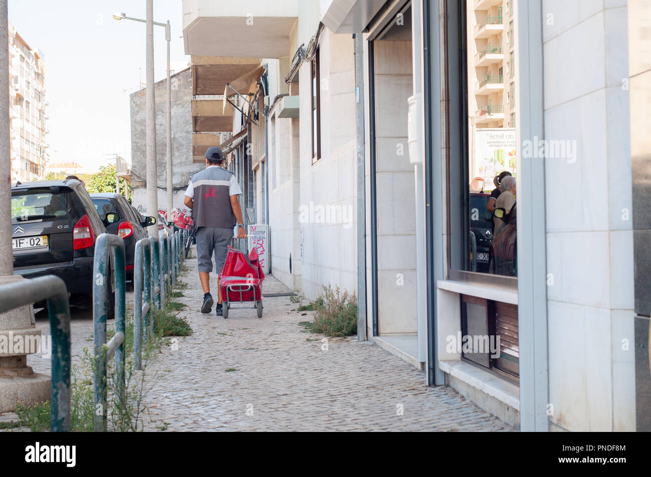 Postman livrer le courrier dans la rue de Lisbonne Banque D'Images