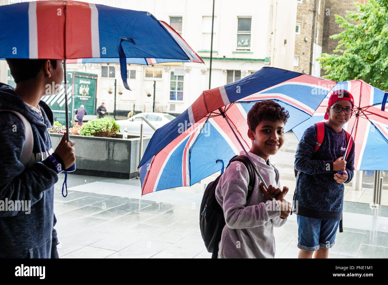 Londres Angleterre,Royaume-Uni,South Bank,Lambeth,pluie jour météo, drapeau Union Jack couleurs parapluies,musulman ethnie garçon garçons,mâle enfant enfants enfants jeunes Banque D'Images