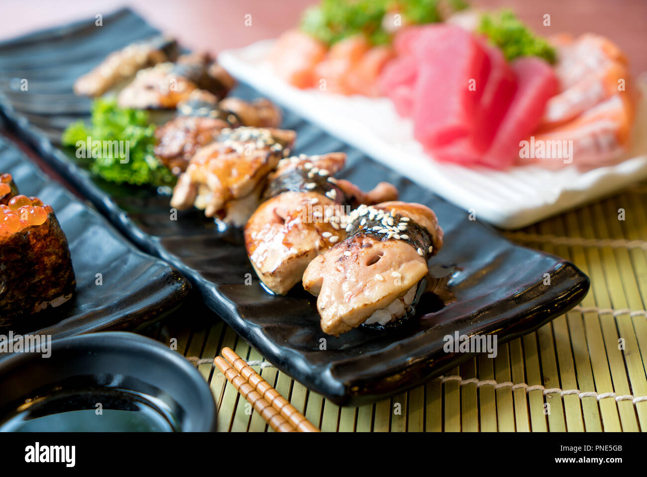 Sushi avec des baguettes et de la sauce de soja. Sushi roll Japanese food in restaurant. Jeu de Sushi de foie gras avec du saumon, thon, oeufs de poisson volant et le caviar closeup Banque D'Images