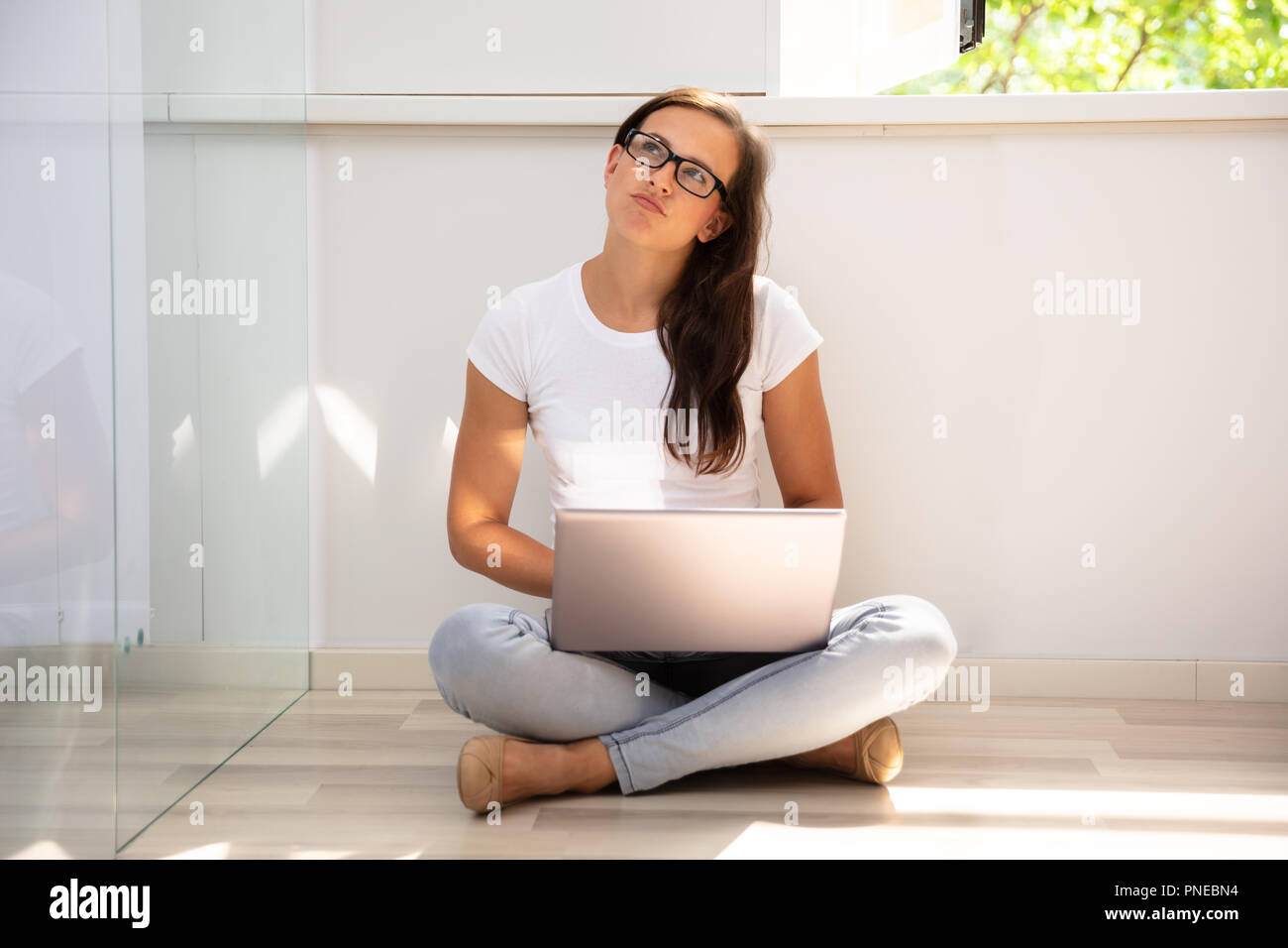 Young Woman Sitting on Floor Using Laptop At Home Banque D'Images