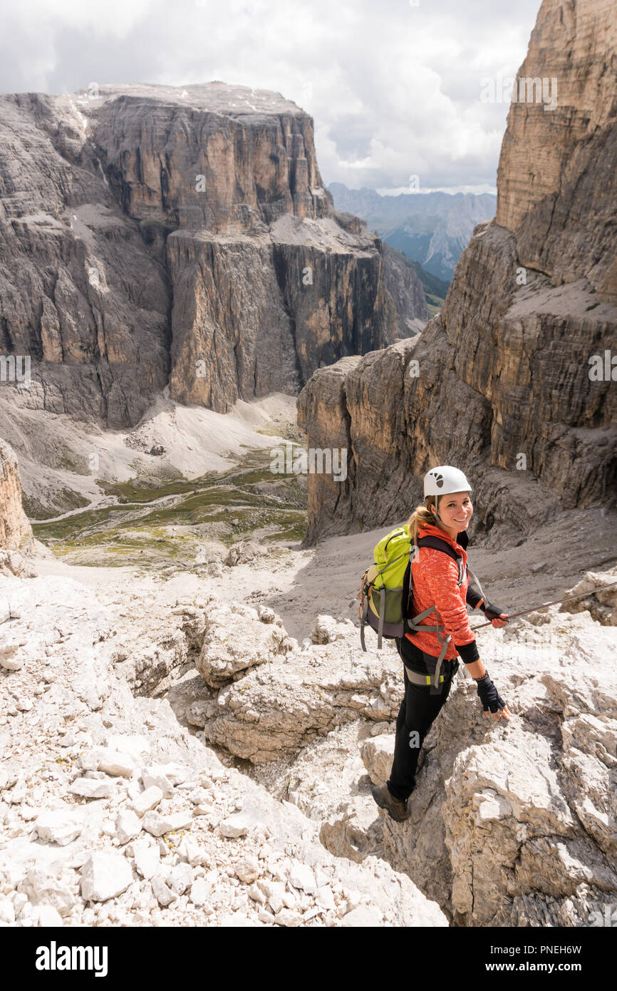 Jeune femme d'alpiniste descendre une pente raide Via ferrata dans les Dolomites d'Alta Badia en Italie du nord avec grand paysage derrière Banque D'Images