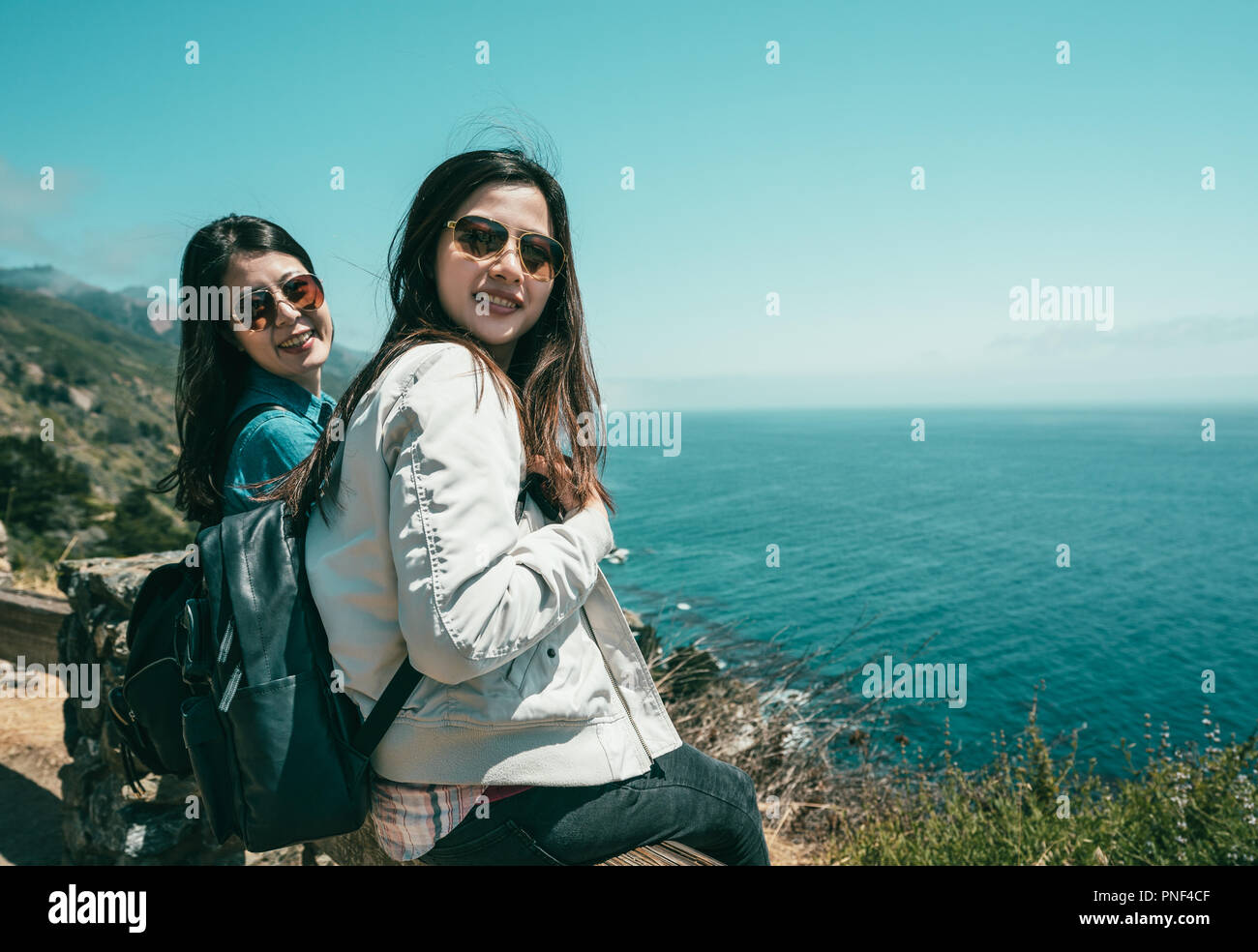 Les jeunes belles filles assis sur le banc ensemble et à heureux avec un arrière-plan de la mer. Banque D'Images