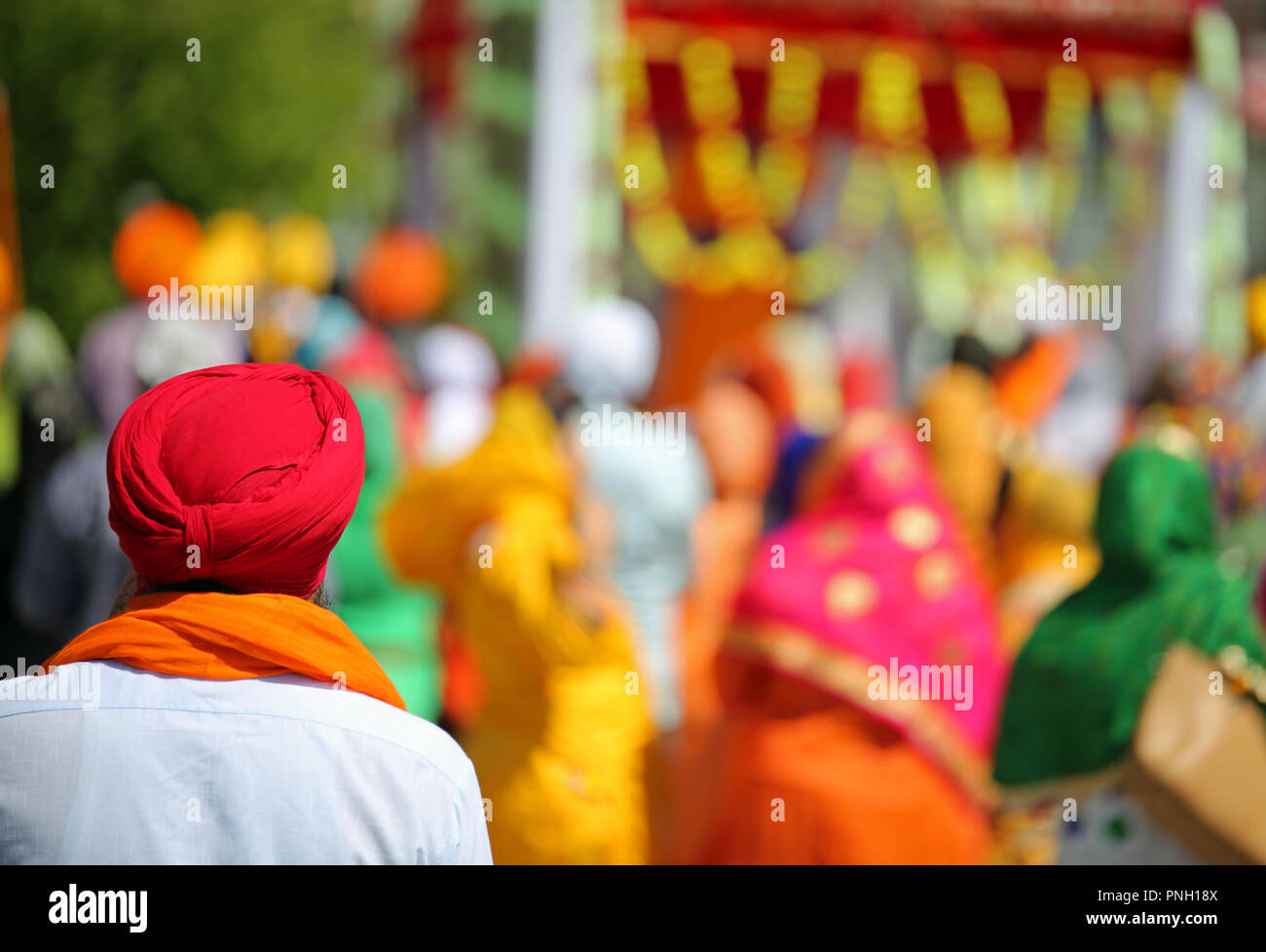Homme sikh avec turban rouge au cours d'un défilé en plein air et plus de personnes Banque D'Images
