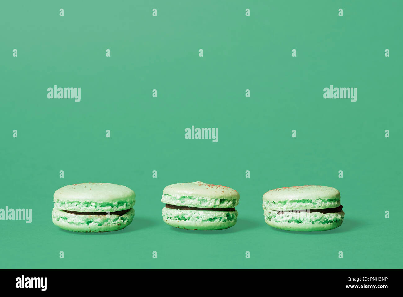Trois macarons menthe verte sur fond vert avec espace pour copier et texte Banque D'Images