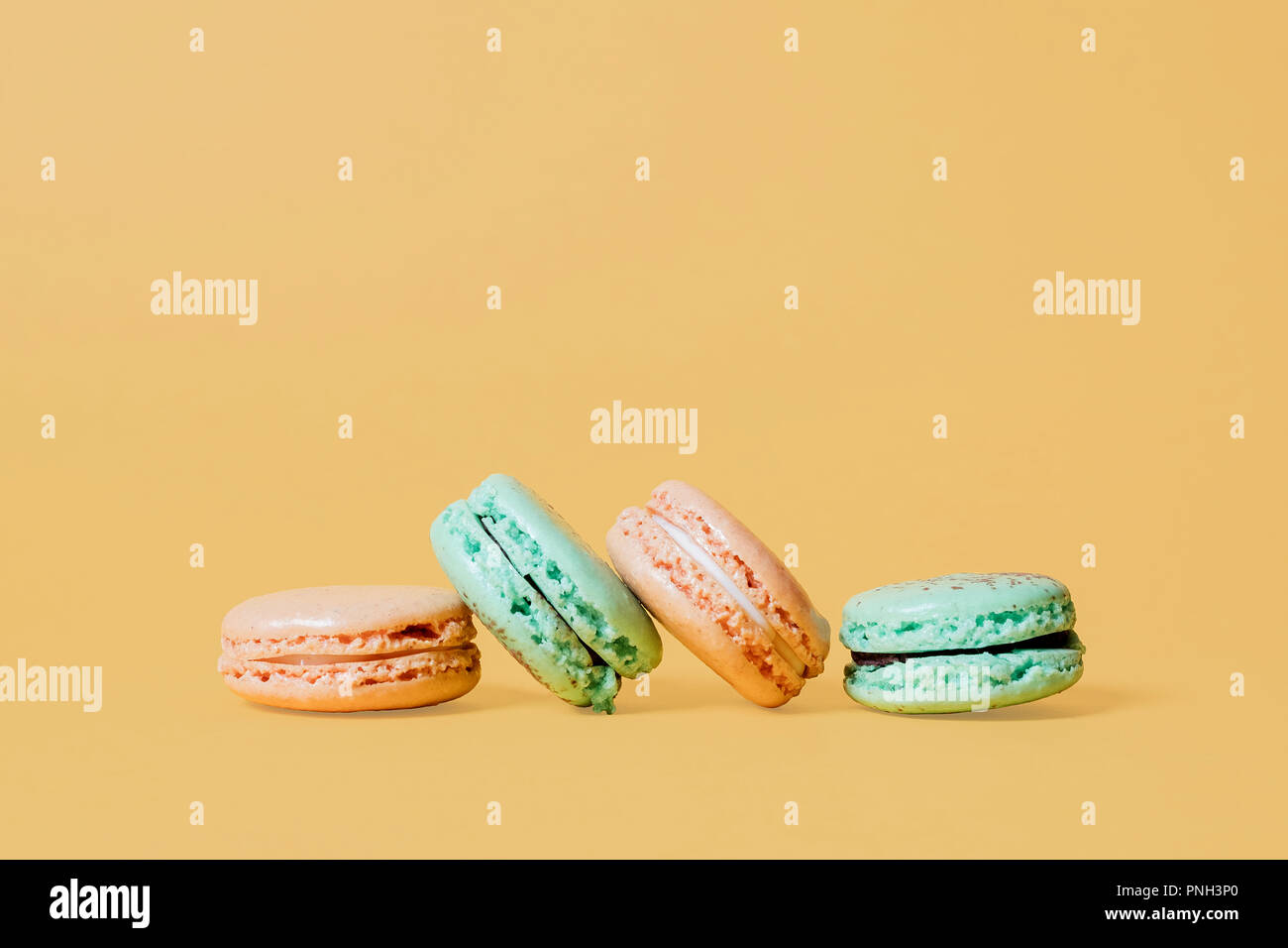 Orange et vert menthe macarons sur un fond orange jaune avec espace pour copier et texte Banque D'Images