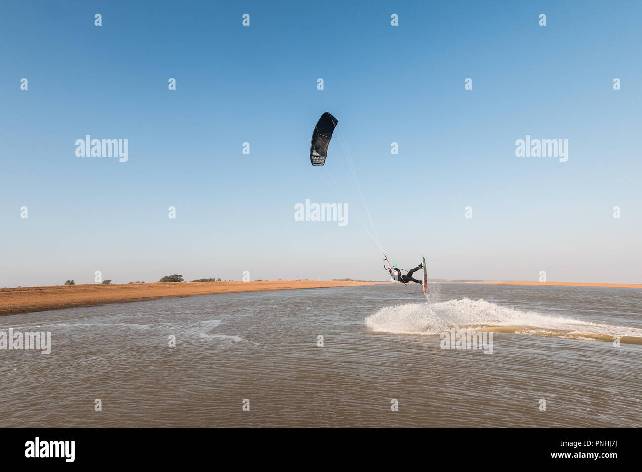 Kiteboarder tirant d'air et d'obtenir des astuces sur un jour d'été parfait avec ciel bleu clair. Strret bardeaux, Suffolk, UK Banque D'Images
