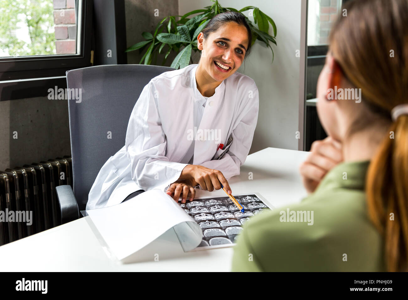 Female doctor smiling plus d'un scanner CT avec un patient. Plan moyen. Banque D'Images