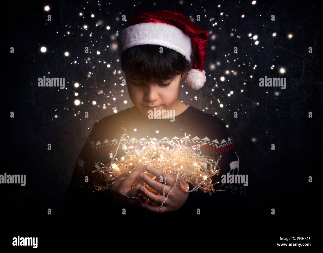 Enfant avec des lumières de Noël sur fond noir Banque D'Images