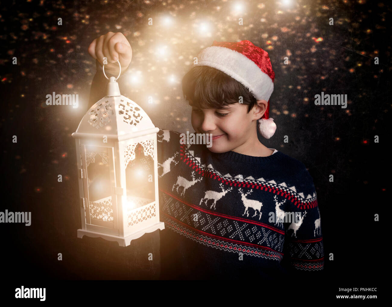 Little Boy holding une vieille lampe sur fond noir Banque D'Images