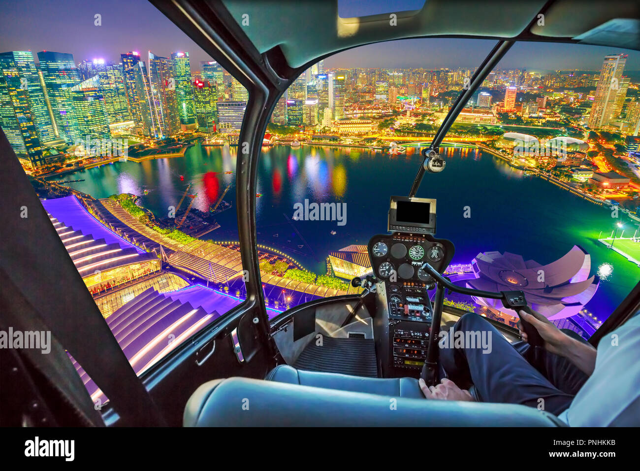 Pilotage d'hélicoptère en vol d'intérieur sur Singapour Marina Bay avec quartier des gratte-ciel de nuit reflétée sur le port. Vol panoramique au-dessus de Singapour. Nuit scène aérienne urbaine. Banque D'Images
