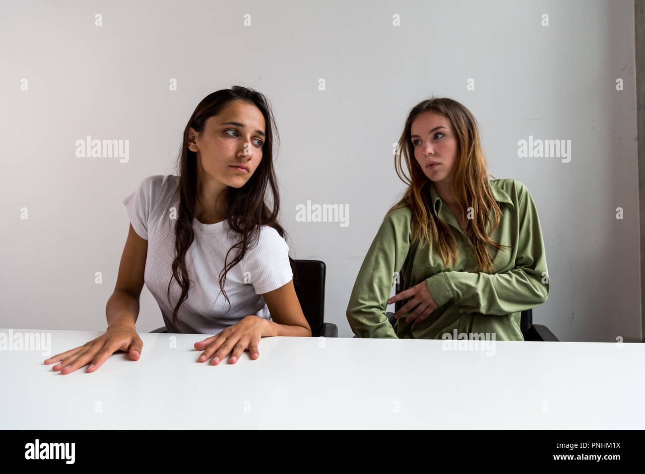 Deux femmes effectuant des poses artistiques assis à grand bureau. Plan moyen. Sur face avant. Banque D'Images