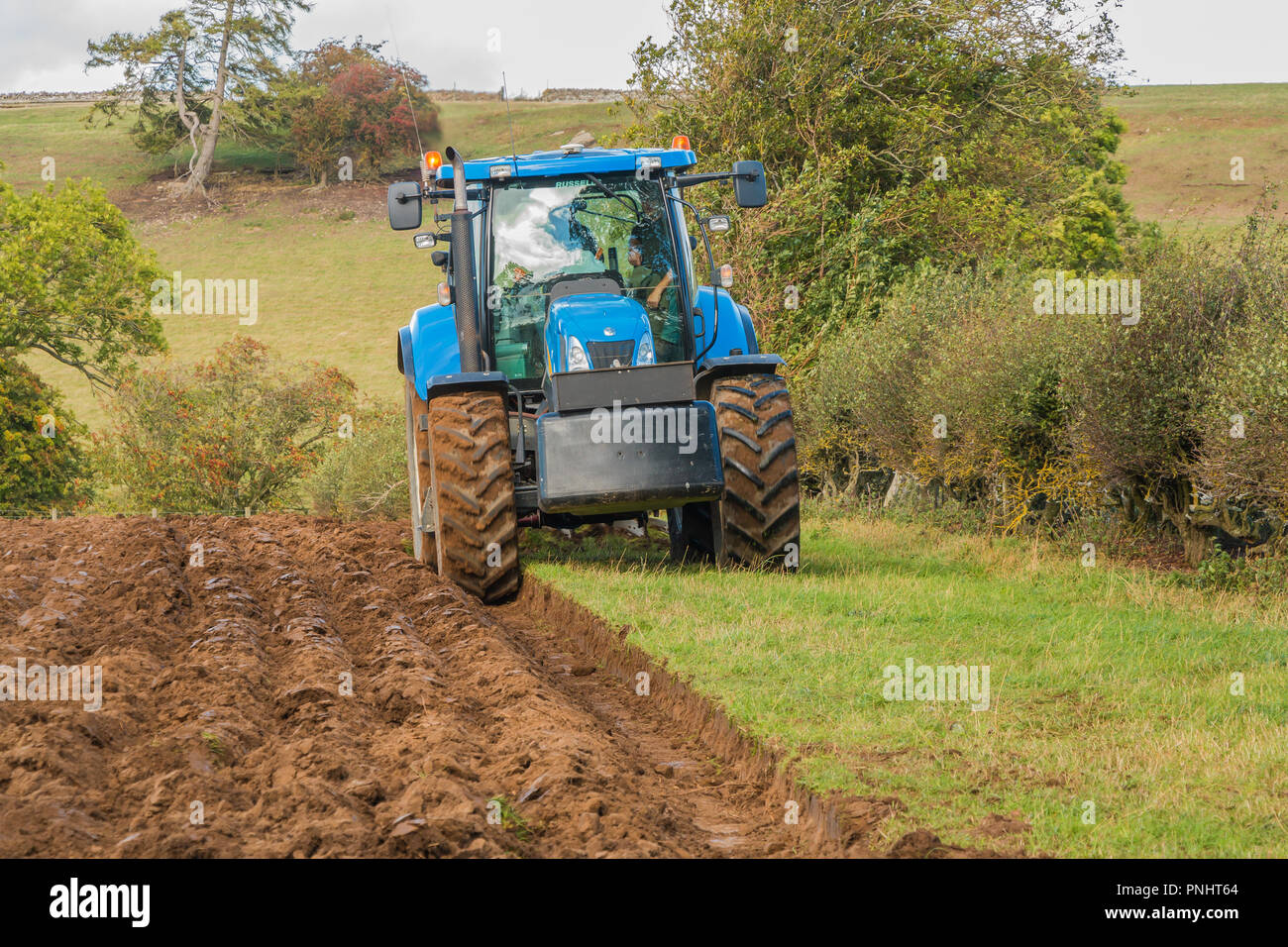 Un tracteur New Holland et labourer au travail en automne Sunshine Banque D'Images