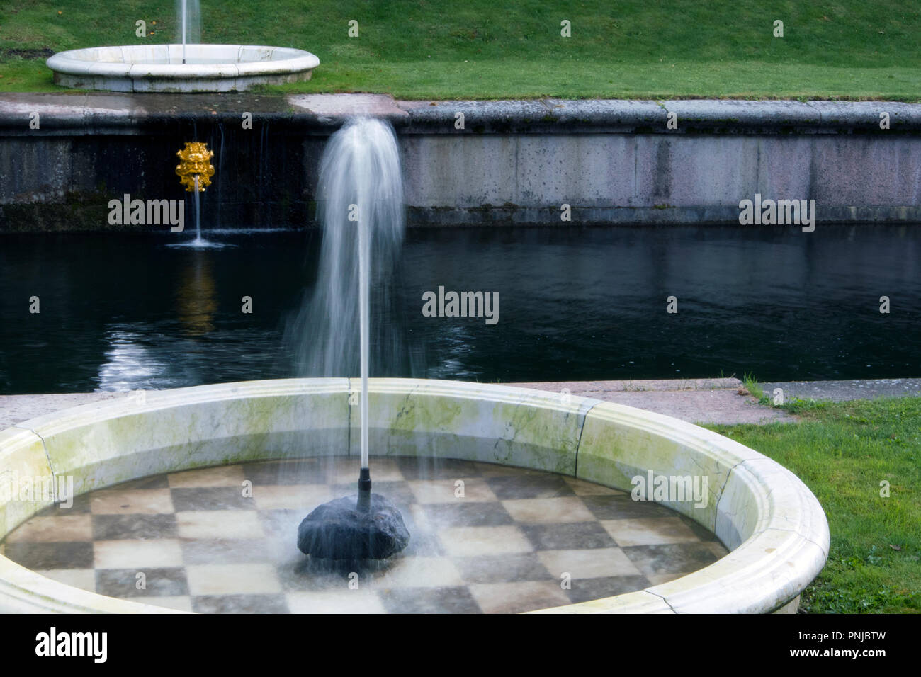 Peu élégante fontaine avec jet lisse dans une piscine ronde à carreaux avec en bas Banque D'Images